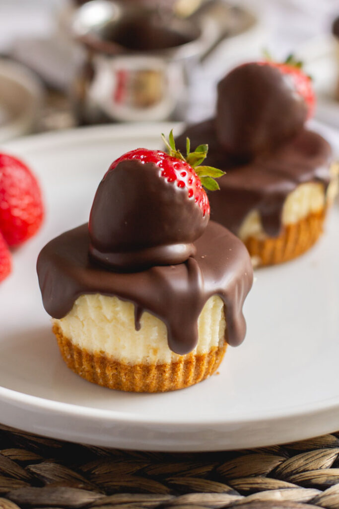 mini cheesecakes on a plate with chocolate covered strawberries on top and chocolate dripping down