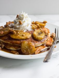 The breakfast in bed of your dreams, these bananas foster pancakes are topped with a rich caramel sauce and served with pecans, whipped cream or vanilla ice cream.
