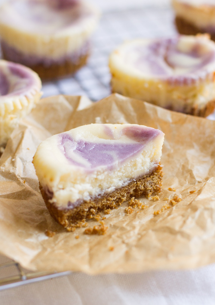 lavender purple and white mini cheesecake cut in half on a piece of brown parchment