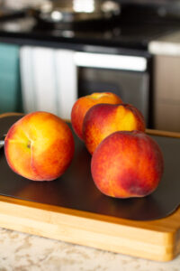 peaches on a cutting board in a kitchen
