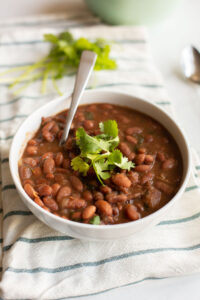 Instant Pot Charro Beans in a white bowl with cilantro on top