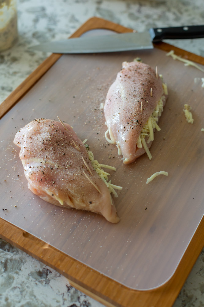 raw chicken being stuffed with spinach artichoke dip