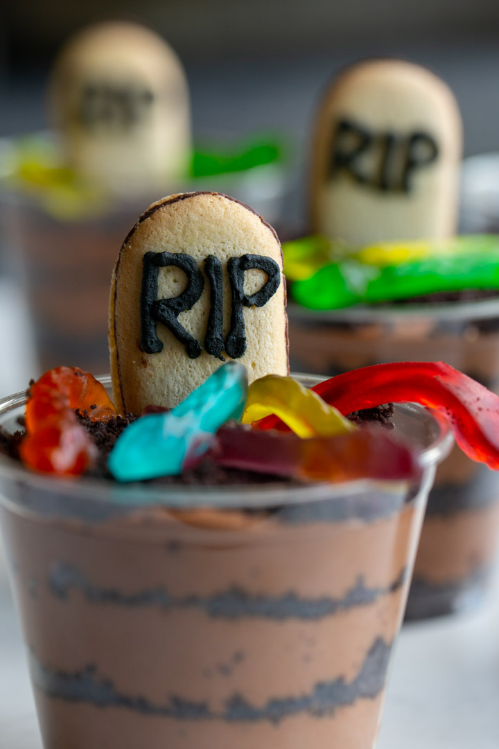 baileys chocolate mousse cups with layers of oreo dirt, gummy worms and a cookie tombstone