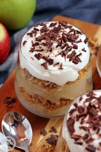 layers of apples, biscuits, whipped cream and chocolate in a glass