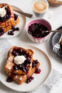 blueberry stuffed french toast on a plate with blueberry sauce and cream