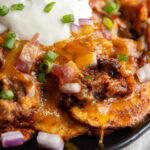 The ultimate appetizer or game day food - these BBQ Potato Nachos are seasoned thinly sliced potatoes piled high with cheese, pulled pork, onions and sour cream!