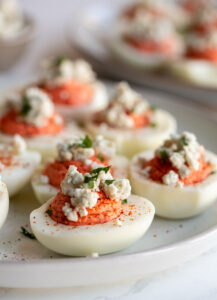 buffalo deviled eggs on a plate topped with blue cheese