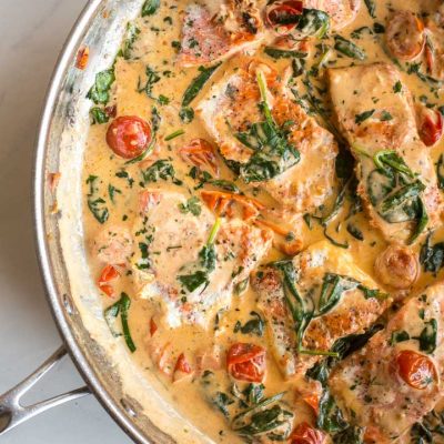 pan seared salmon with spinach and tomatoes in a skillet