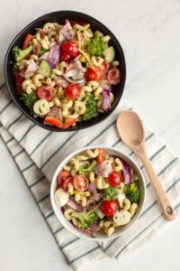 Italian pasta salad in a bowl on a table with a wooden spoon