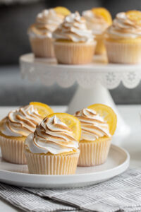 lemon meringue cupcakes topped with candied lemons on a plate