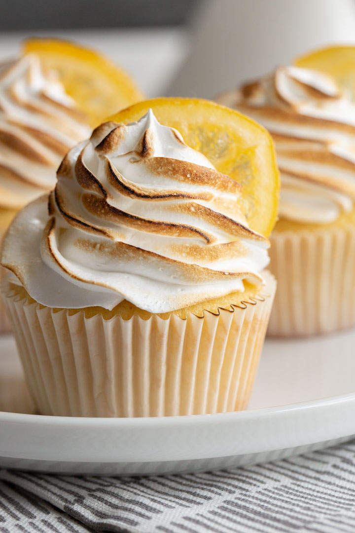 lemon meringue cupcakes with a marshmallow frosting that has been slightly charred with a candied lemon on top