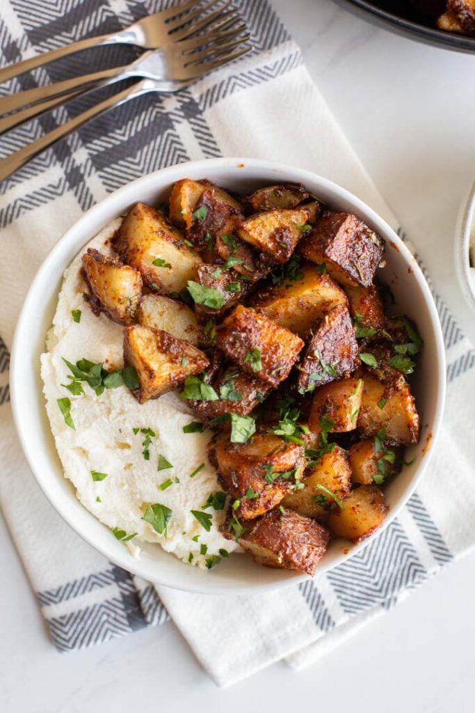 sweet and spicy roasted potatoes in a bowl with ricotta cheese and honey