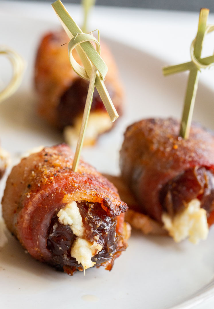 bacon wrapped dates with a special rub on a plate with a decorative toothpick