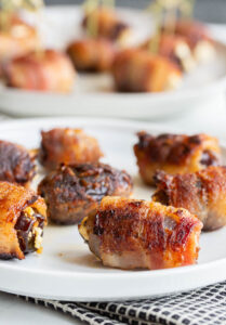 bacon wrapped dates on a plate with a towel