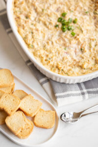 hot crab dip in a casserole dish with toast