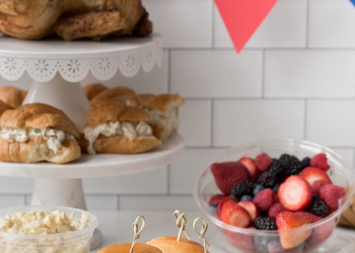 bbq sliders, fresh fruit, cookies, sandwiches and chicken laid out in a party spread