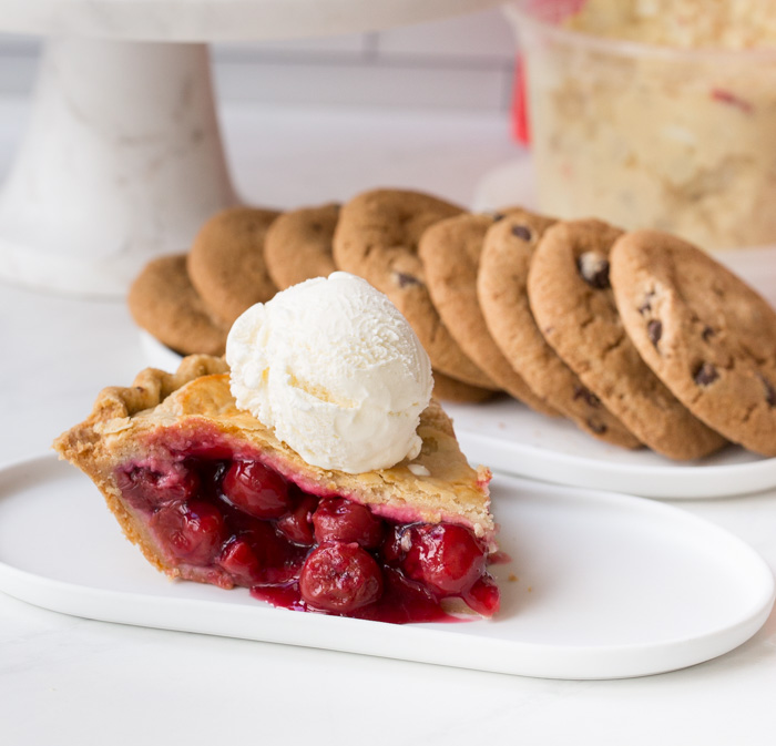 cherry pie on a plate with ice cream and cookies