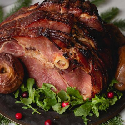 a glazed holiday ham served with baked apples, arugula and cranberries