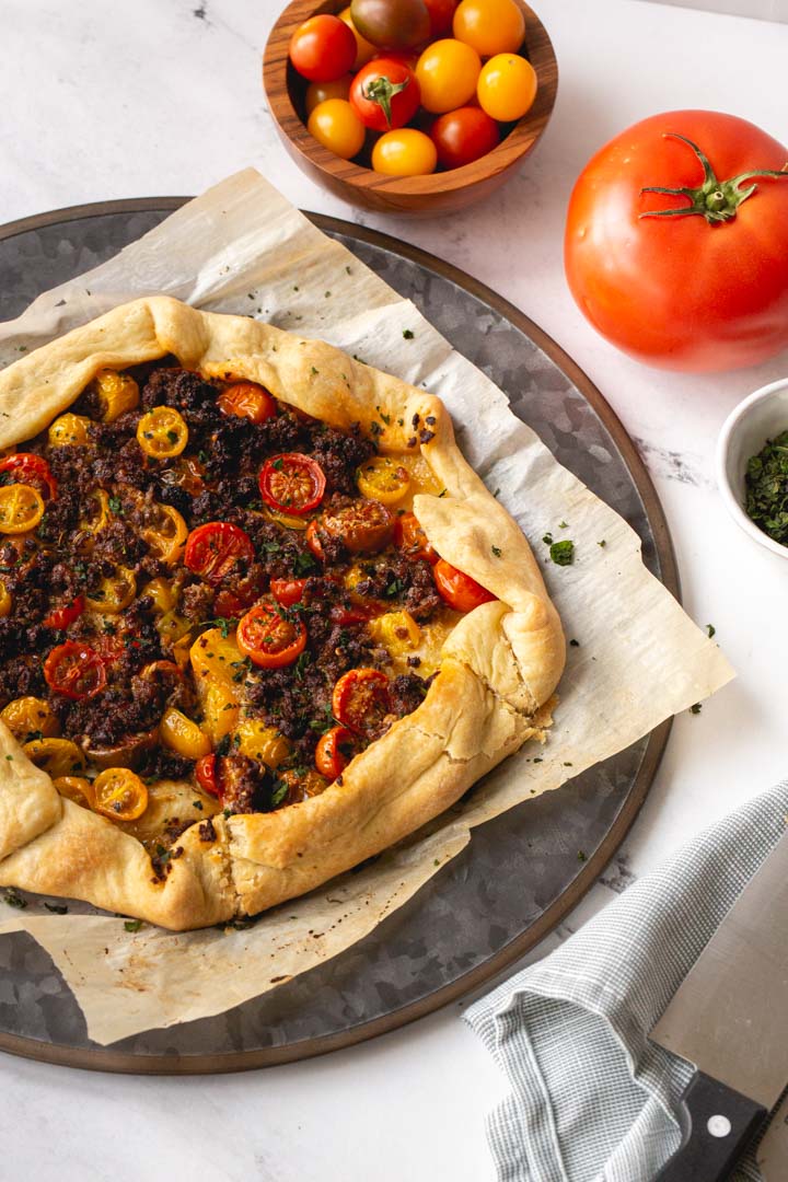 tomato galette with impossible meat and basil on a serving plate