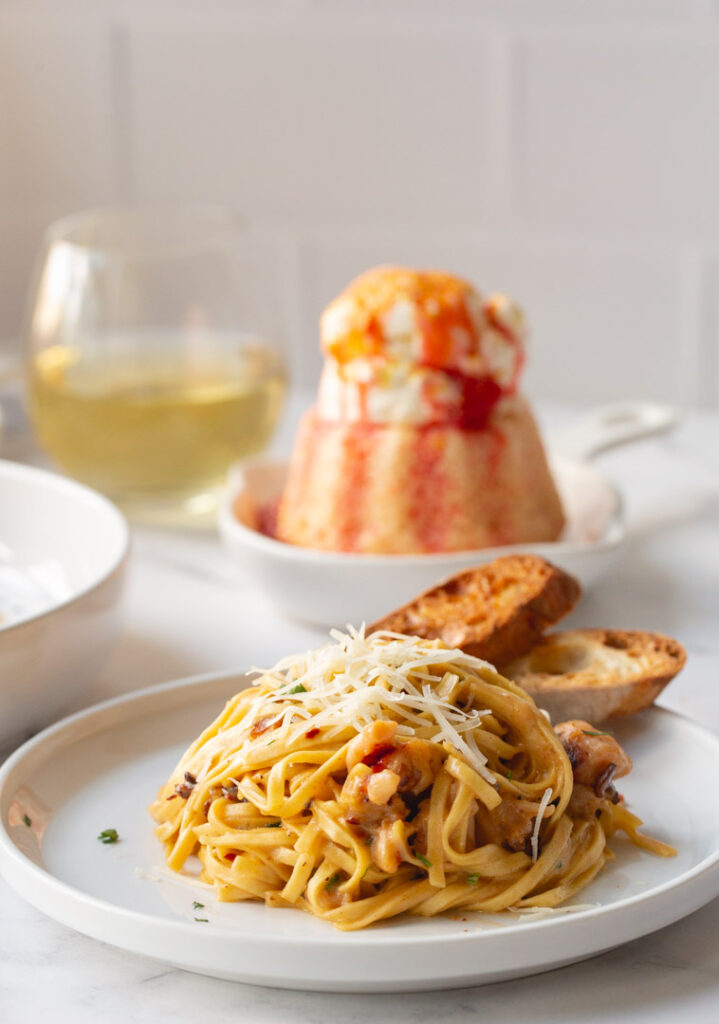 lobster pasta on a plate garnished with gruyere and toasted sourdough bread