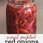 red onions in brine in mason jar on stainless steel counter with text overlay "sweet pickled red onions"